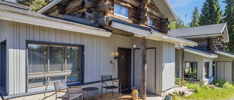 A log cabin with a porch, outdoor seating, and a stone foundation.