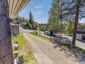 A gravel driveway leading to a building with a wooden exterior, surrounded by trees and a clear sky. - Rukaköngäs 27 by Interhome (Kuusamo)