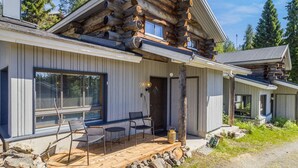 A log cabin with a wooden deck, stone walls, and a large window. - Rukaköngäs 27 by Interhome (Kuusamo)