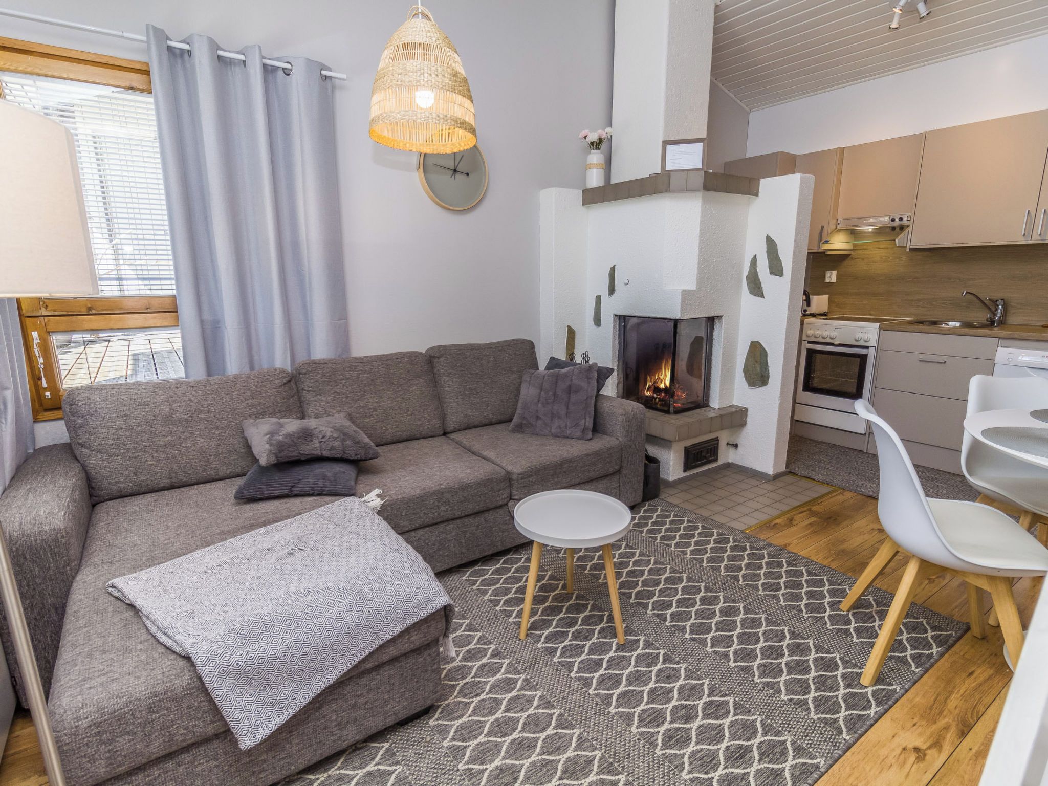 Un salon moderne avec un canapé gris, une petite table ronde et une cheminée.
