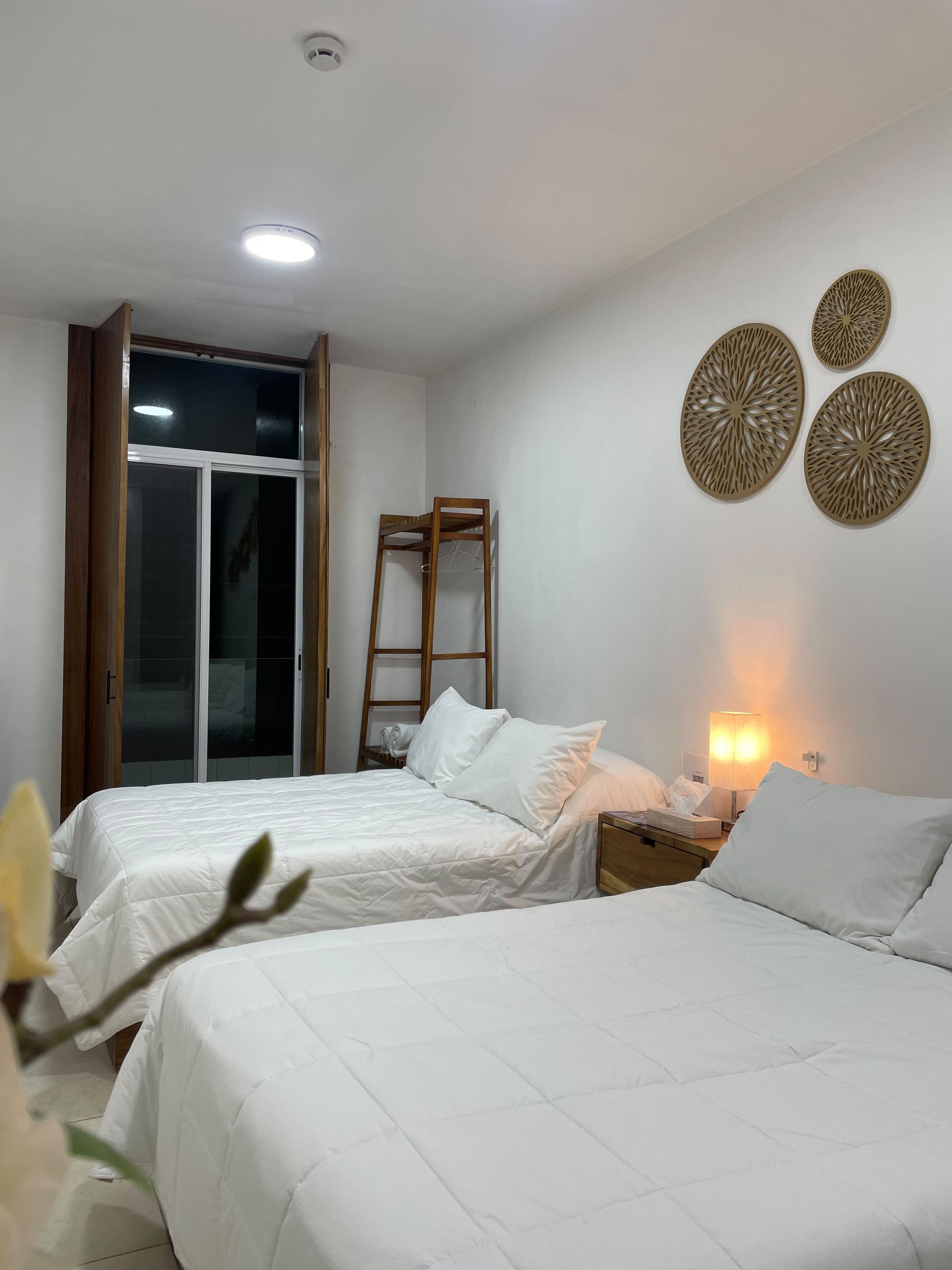 A hotel room with two beds, a ladder, a wall-mounted decorative item, and a sliding door.