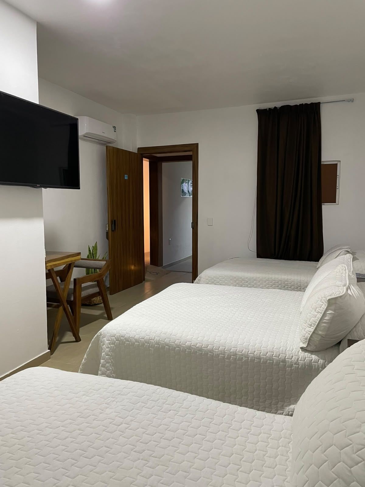 Habitación de hotel con dos camas, un escritorio, una silla, un televisor de pantalla plana y un equipo de aire acondicionado.