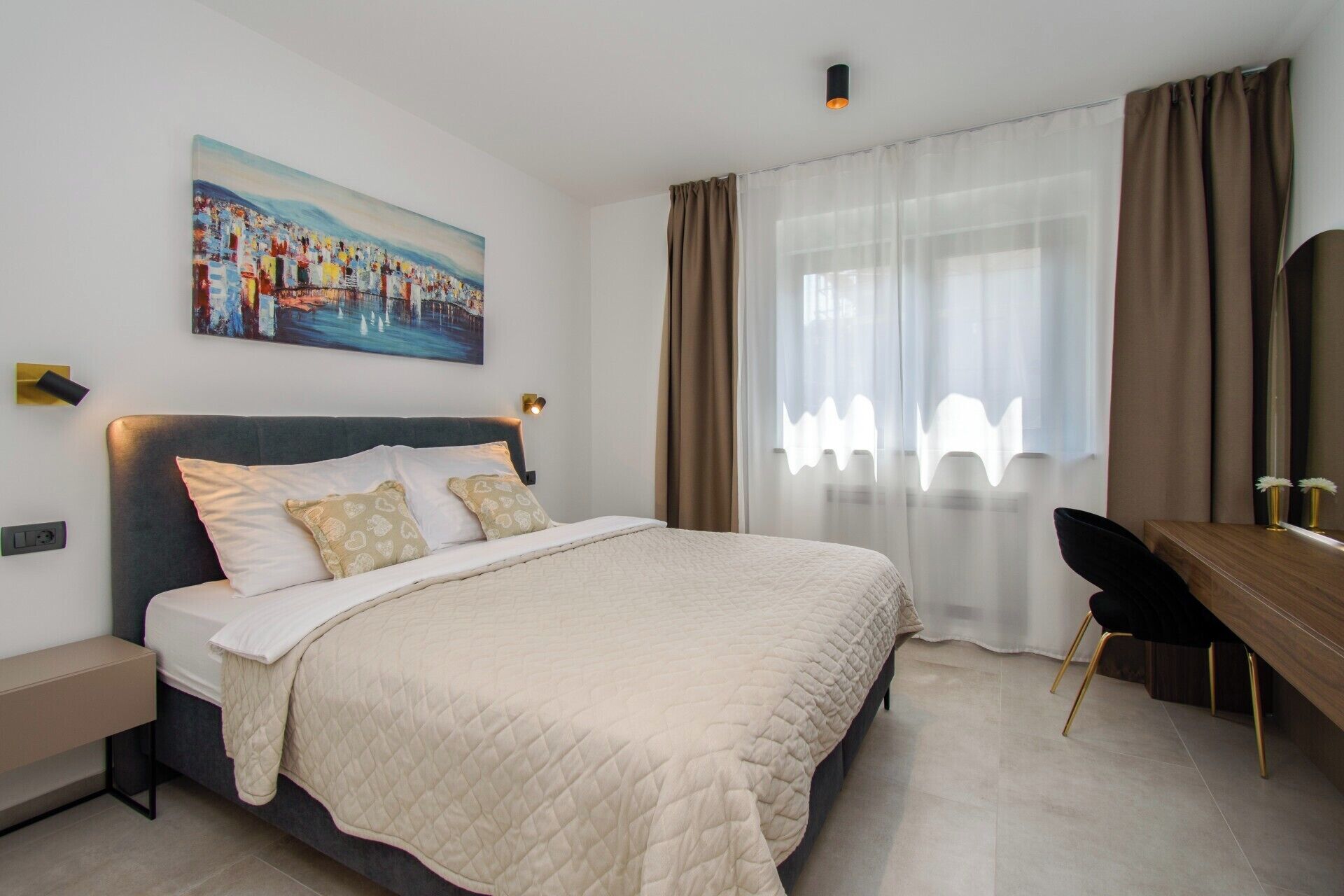 A modern hotel room with a large bed, a desk, and a painting on the wall.