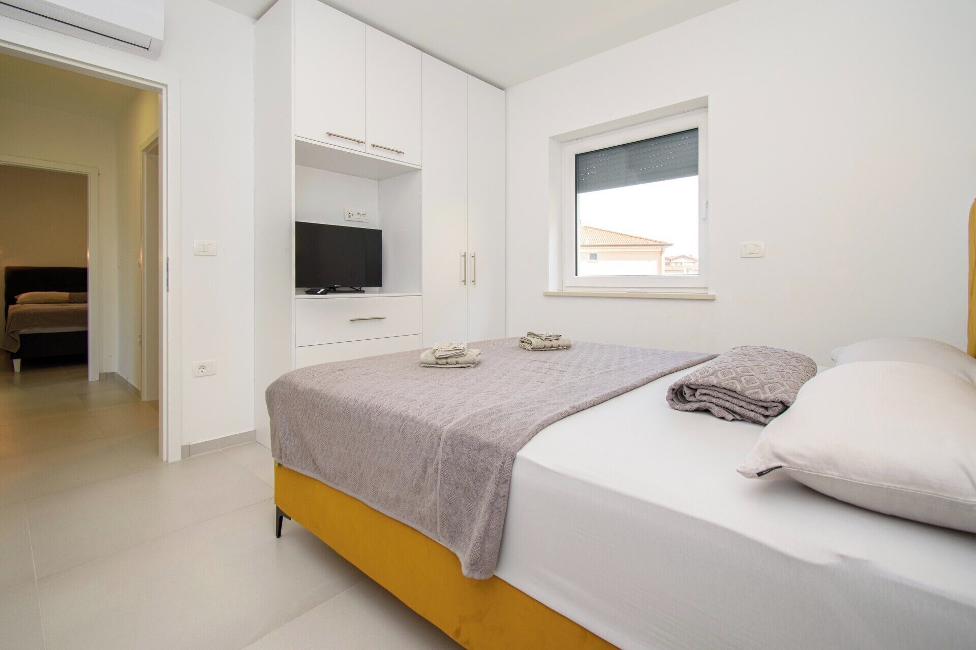 A bedroom with a bed, a TV, and a window.