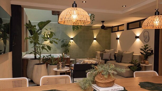 Ein modernes Wohnzimmer mit einer Couch, einem Esstisch und hängenden Rattanlampen.