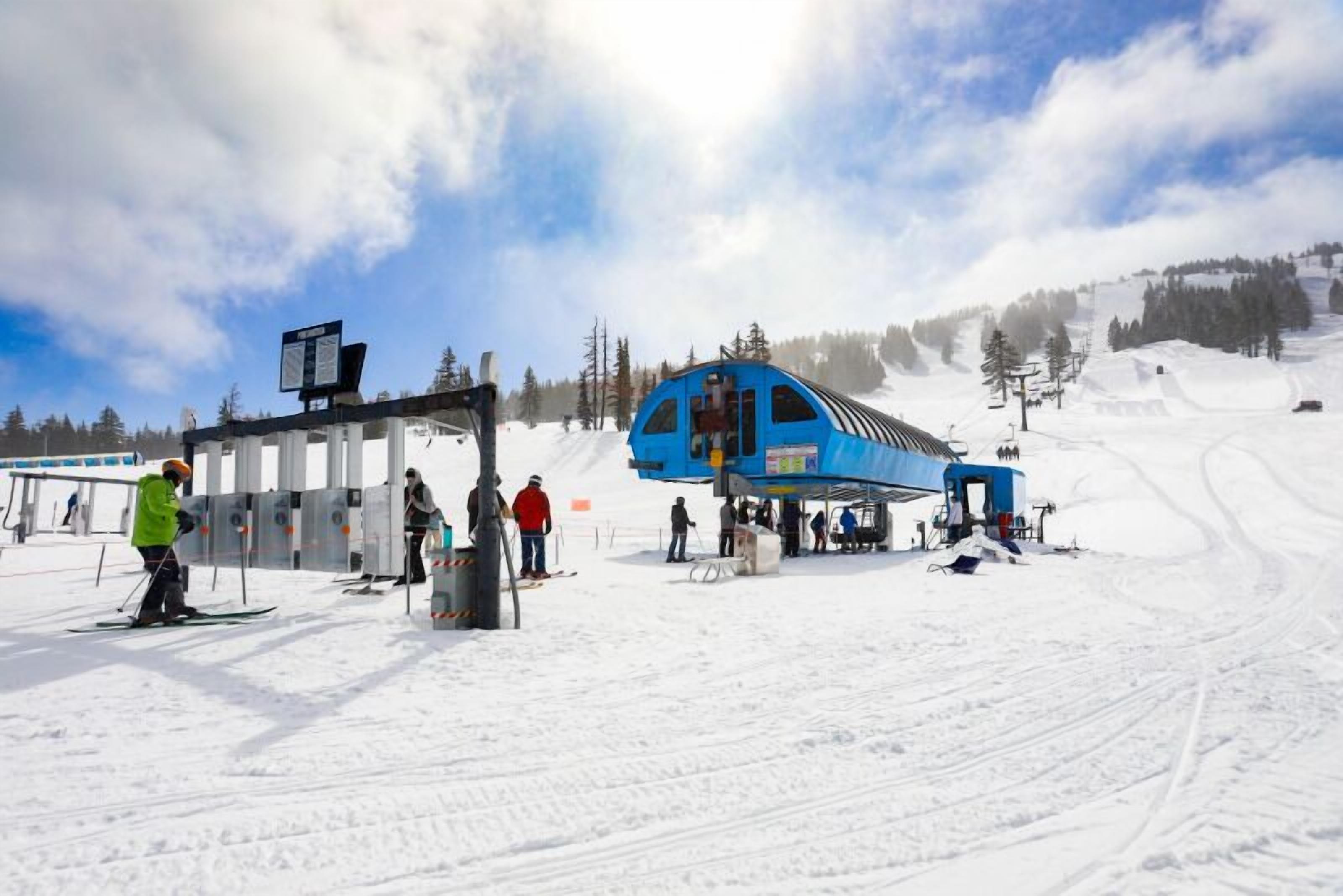 A ski lift station with a blue lift chair and a control panel.