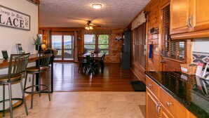 A spacious kitchen with wooden cabinets, a dining area with chairs, and a view of the outdoors. - Heavens Hideaway - 4 bedroom with views, allows pets, game tables (Lenoir)