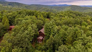 A cabin surrounded by dense forest, with a view of distant mountains under a cloudy sky. - Heavens Hideaway - 4 bedroom with views, allows pets, game tables (Lenoir)
