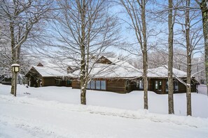A wooden cabin with a snow-covered roof, surrounded by trees. - Adventure Starts at Your Door B10 (Killington)