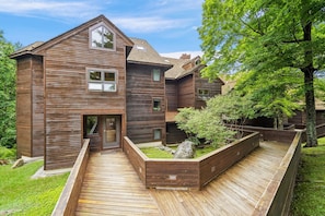 Een modern houten huis met een schuin dak, een voortuin en een aangelegde tuin met een houten terras.
