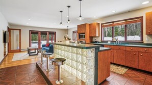 A modern kitchen with a central island, wooden cabinets, and a large window providing a view of the outdoors. - 3 Bedroom Pet Friendly with Hot Tub Birch Beauty (Killington)