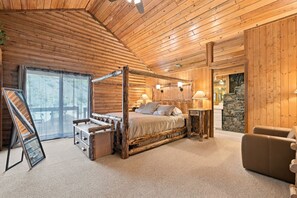 Une chambre à coucher dans un chalet en rondins, avec un lit à baldaquin, un bureau et un mur décoratif en pierre.