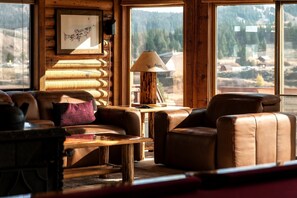 L’intérieur d’un chalet chaleureux, avec un canapé en cuir, une table et une lampe.