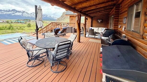A wooden deck with outdoor seating, a grill, and a view of mountains. - Stanley House - Hillside Cabin with Panoramic Views of the Sawtooth Mountains (Stanley)