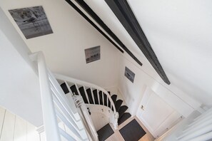 A staircase with white railings, black steps, and a white door at the bottom. - Ananda, App. 13 - Gemütliche 2-zimmer Og-ferienwohnung auf ca. 45 m² Wohnfläche, für 2 Personen (Wenningstedt-Braderup (Sylt))