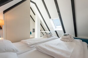 Een kamer met twee bedden, een dakraam en uitzicht op de omgeving.
