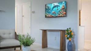 A living room with a sofa, a coffee table with a plant, a wooden side table, and a painting of an underwater scene. - Entire Home: 4 Blocks to Ocean-Jacksonville Beach (Jacksonville Beach)