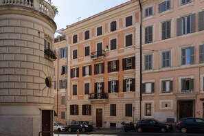 Un edificio de varios pisos con un estilo arquitectónico clásico, que presenta una entrada central con una puerta y ventanas en cada planta.