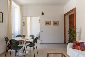 A dining area with a round table and chairs, a white sofa, and a plant. - Panisperna 193 - FromHometoRome (Roma)