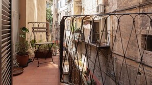 A narrow outdoor corridor with a metal gate, potted plants, and a small table. - Panisperna 193 - FromHometoRome (Roma)