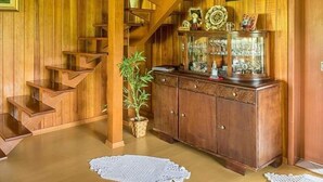 A wooden staircase leading to a second floor, a wooden cabinet with glass display, and a small potted plant. - Pousada Rota das Cachoeiras Urupema (Urupema)