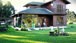 A two-story wooden house with a large glass front, a balcony, and a satellite dish. - Pousada Rota das Cachoeiras Urupema (Urupema)