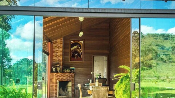 A modern interior with a glass wall, wooden ceiling, and a fireplace. - Pousada Rota das Cachoeiras Urupema (Urupema)