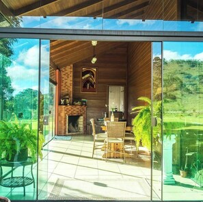 A modern interior with a glass wall, wooden ceiling, and a fireplace.