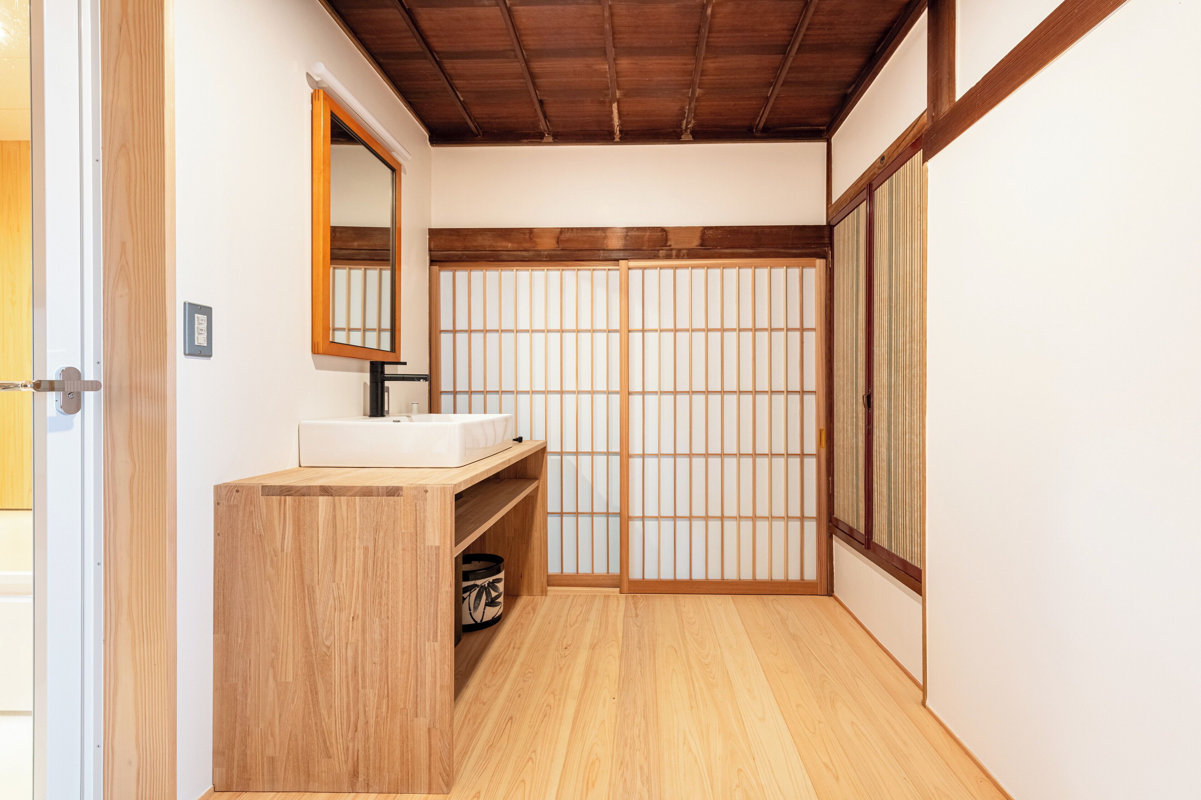 A traditional Japanese-style bathroom with a wooden vanity, a mirror, and sliding doors.