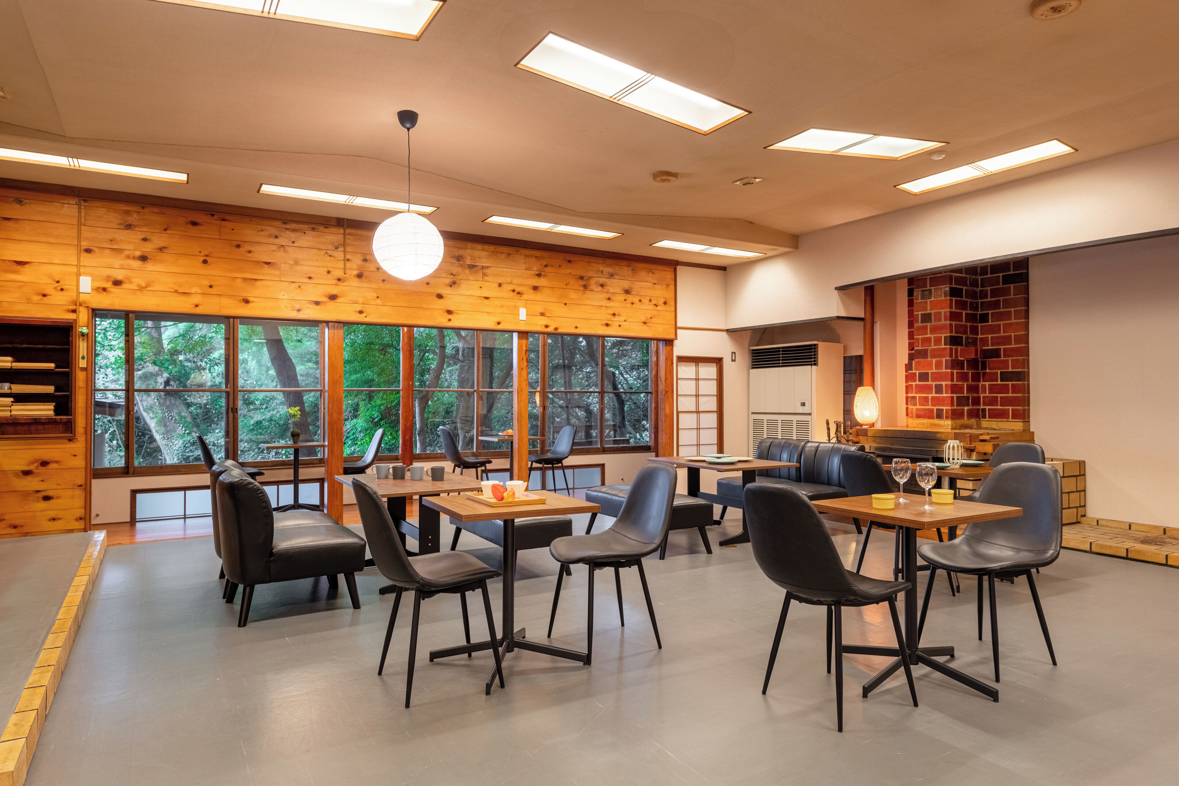 Un comedor moderno con paredes de madera, ventanas amplias y sillas negras.