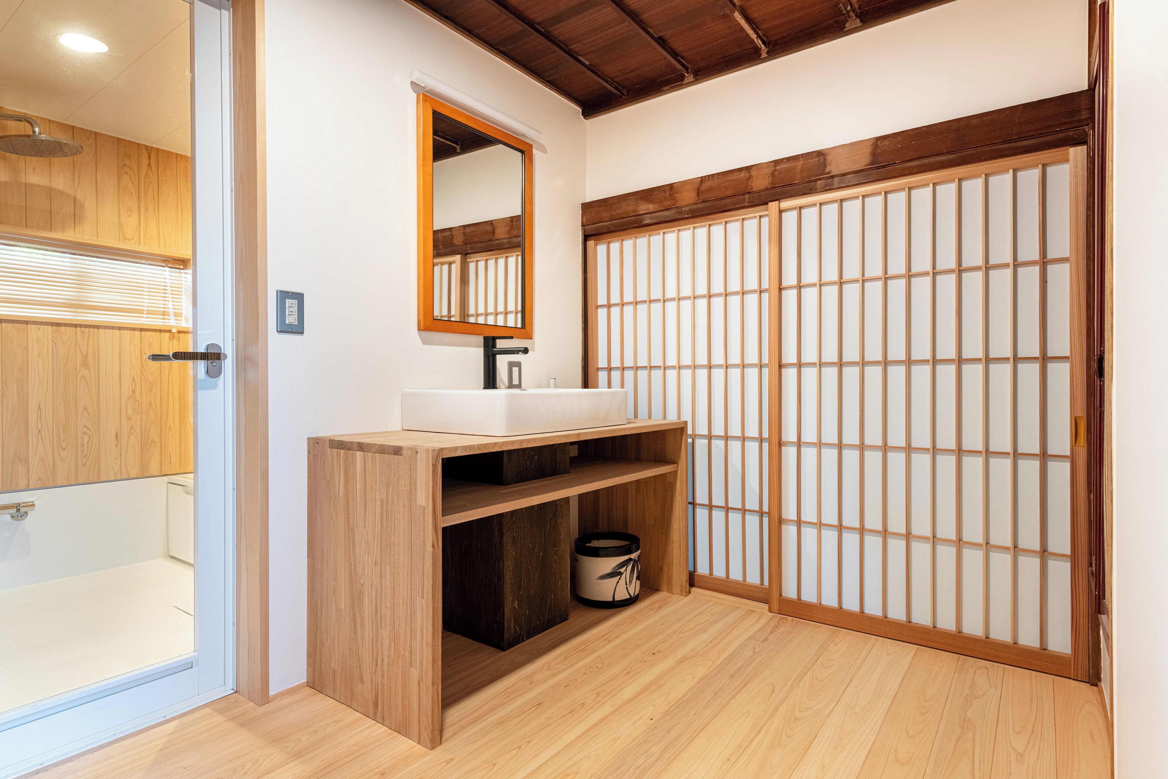 A bathroom with a wooden vanity, a mirror, a sink, and a shoji screen door.