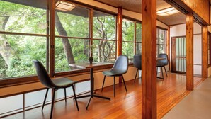 Un intérieur moderne avec de grandes fenêtres, un plancher en bois et un coin salon avec des fauteuils.