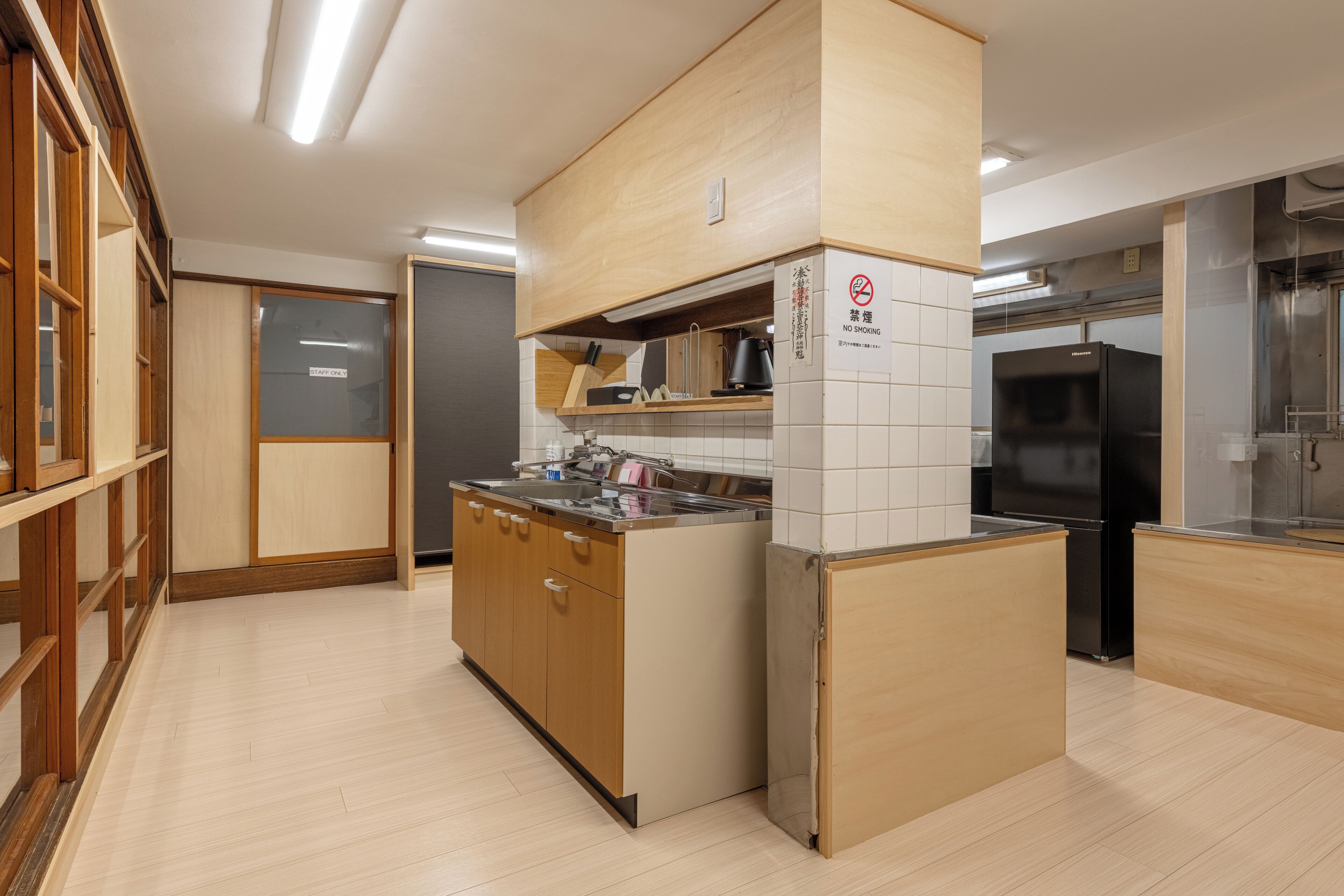 A modern kitchen with wooden cabinets, a stainless steel sink, and a black refrigerator.