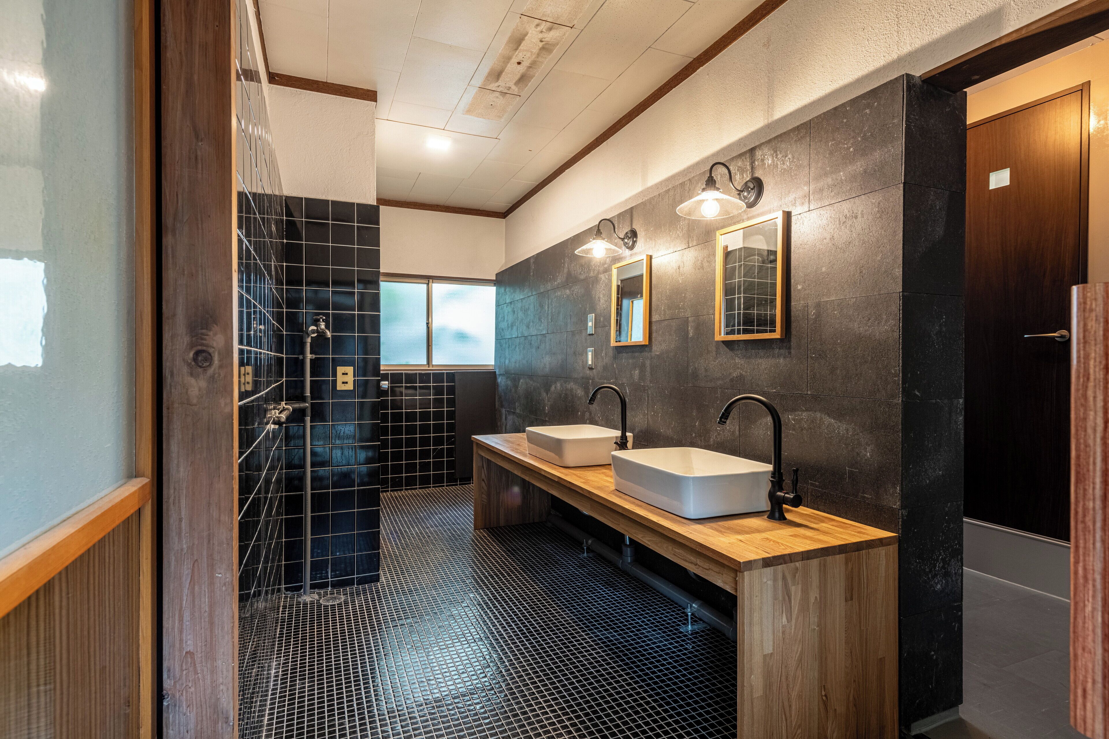 Un baño moderno con dos lavamanos, ducha y un espejo grande.