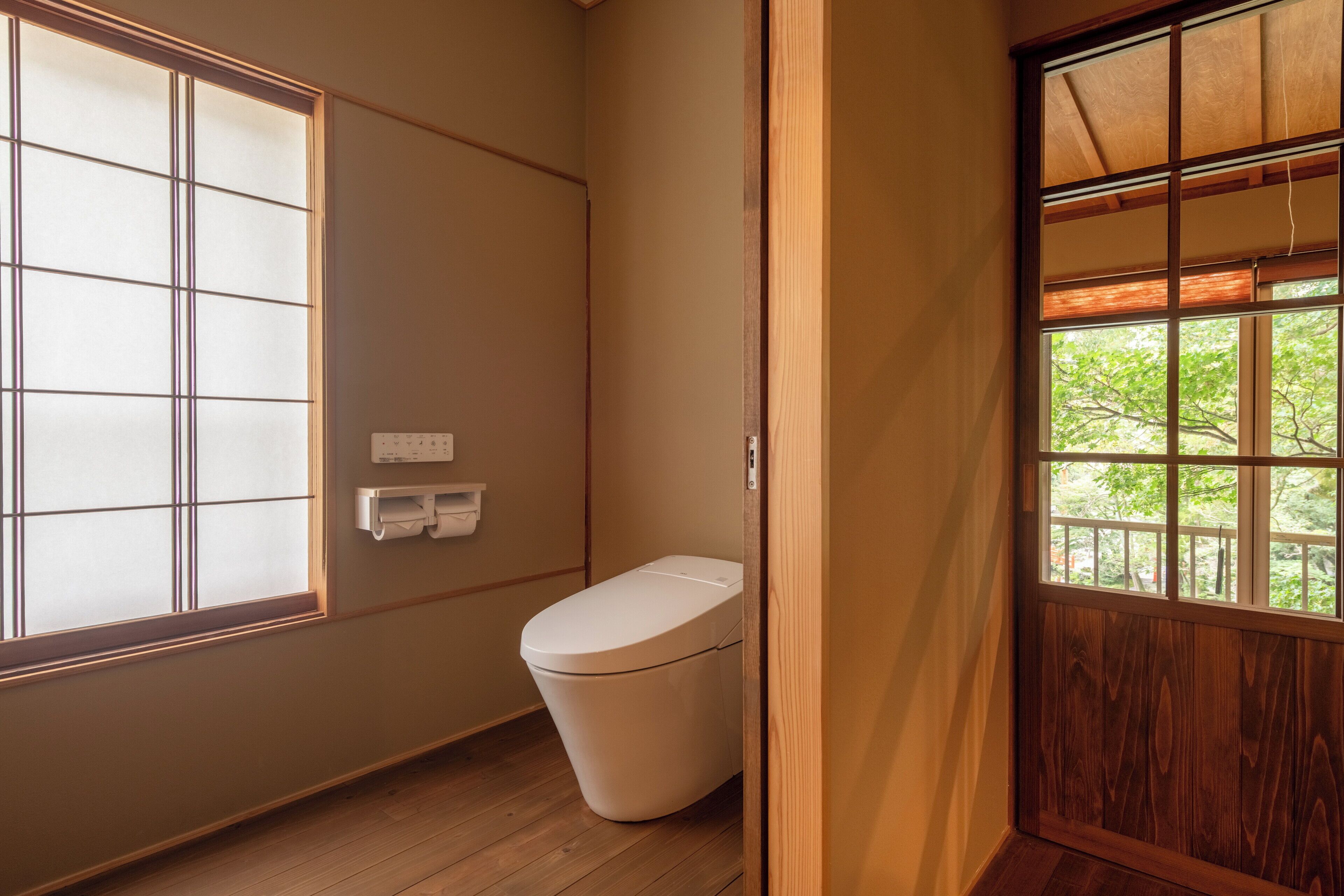 Ein Badezimmer mit Toilette, Fenster und Holztür.
