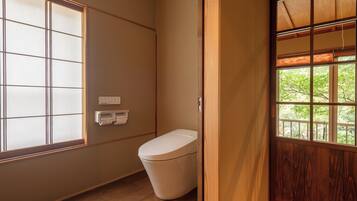 Ein Badezimmer mit Toilette, Fenster und Holztür.