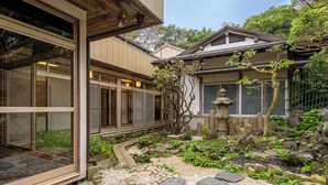 Un jardin japonais traditionnel avec un sentier de pierres, un petit arbre et une lanterne en pierre.