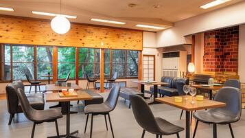 A modern dining area with wooden walls, large windows, and a brick fireplace.