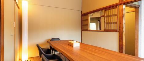 A conference room with a wooden table, black chairs, a standing lamp, and a traditional Japanese shoji screen.