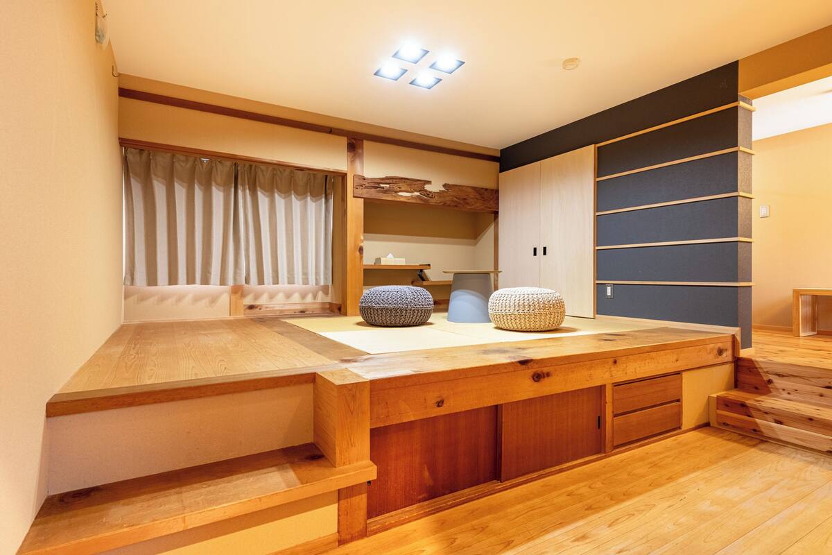 Una habitación moderna con escritorio de madera, estantes empotrados y un amplio ventanal con cortinas.