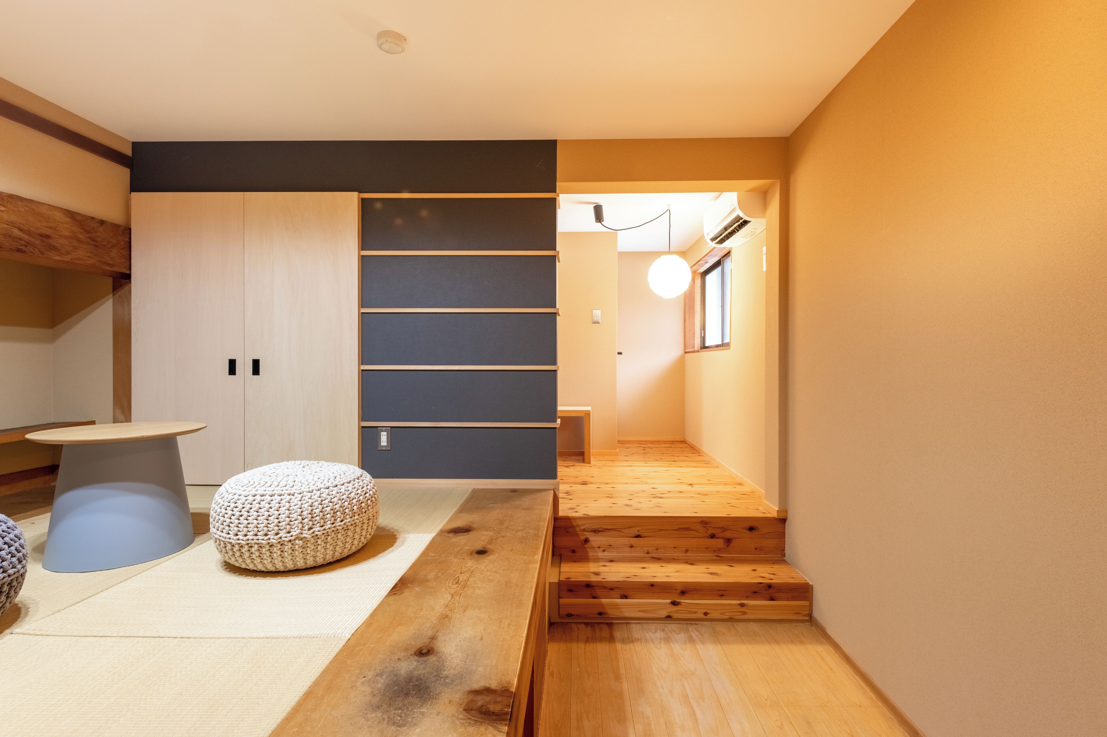 Un interior modern amb una escala de fusta, un matalàs de tatami i un disseny minimalista.
