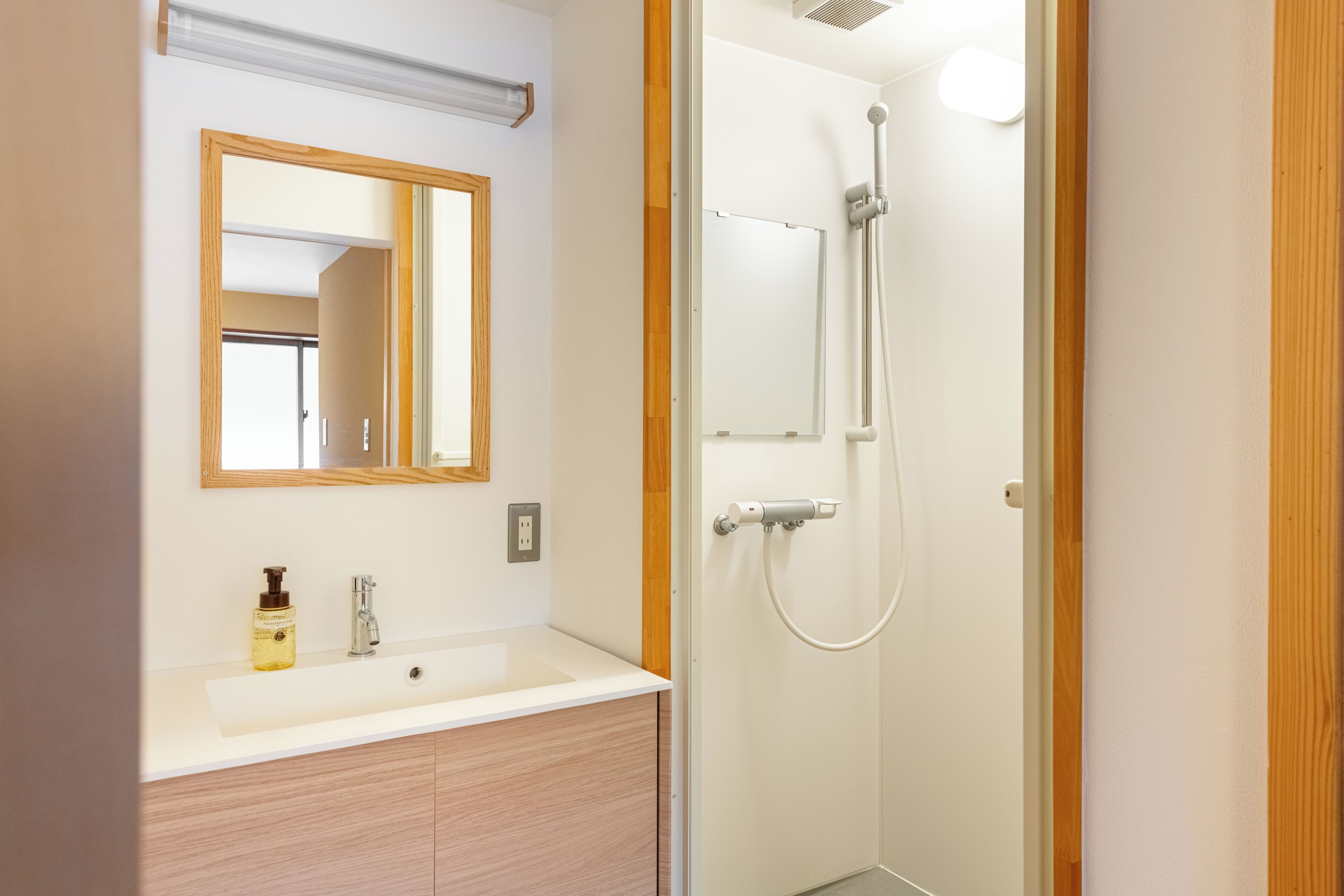 A bathroom with a wooden vanity, a mirror, and a shower with a handheld showerhead.
