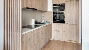 Une cuisine moderne avec des meubles en bois, un plan de travail noir et des appareils électroménagers intégrés.