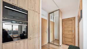 Une cuisine moderne dotée d’appareils électroménagers intégrés, d’un meuble en bois et d’une porte en verre donnant sur une pièce.
