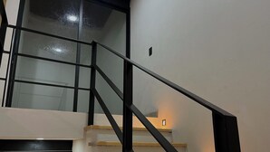 Una escala moderna amb barana de vidre i graons de fusta, que condueix a un pis superior.