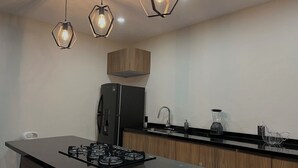 Una cuina moderna amb una illa central, electrodomèstics negres i armaris de fusta.