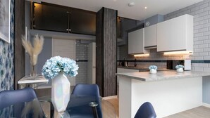 A modern kitchen with a central island, dark cabinetry, and a white backsplash. - Palm Tree House - Winter Wonderland (Greater London)