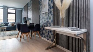 A modern living room with a dining area, featuring a sofa, chairs, a dining table, and a decorative vase. - Palm Tree House - Winter Wonderland (Greater London)