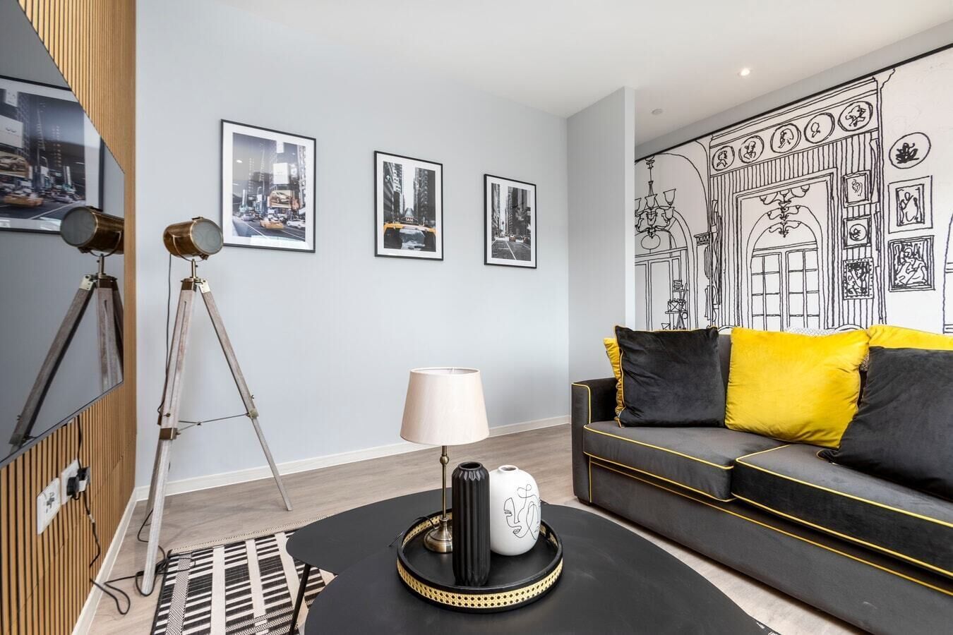 A modern living room with a sofa, a lamp, and framed pictures on the wall.
