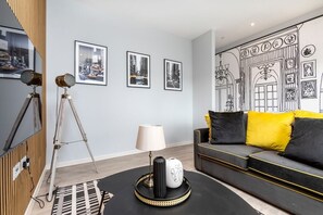 A modern living room with a sofa, a lamp, and framed pictures on the wall. - Palm Tree House - New York (Greater London)